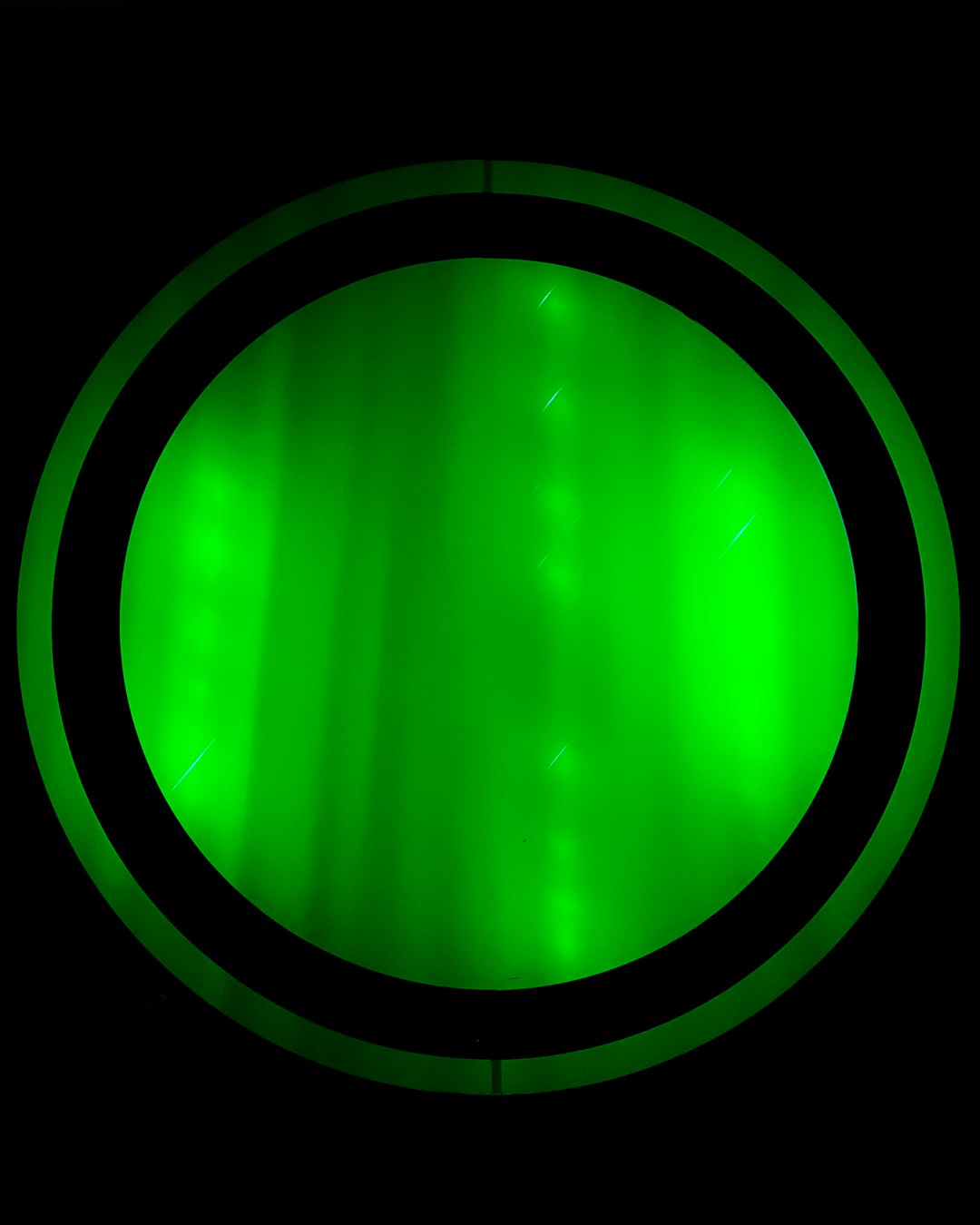 Close view of green optical sensor light glowing in darkness, illustrating PPG sampling pulses
