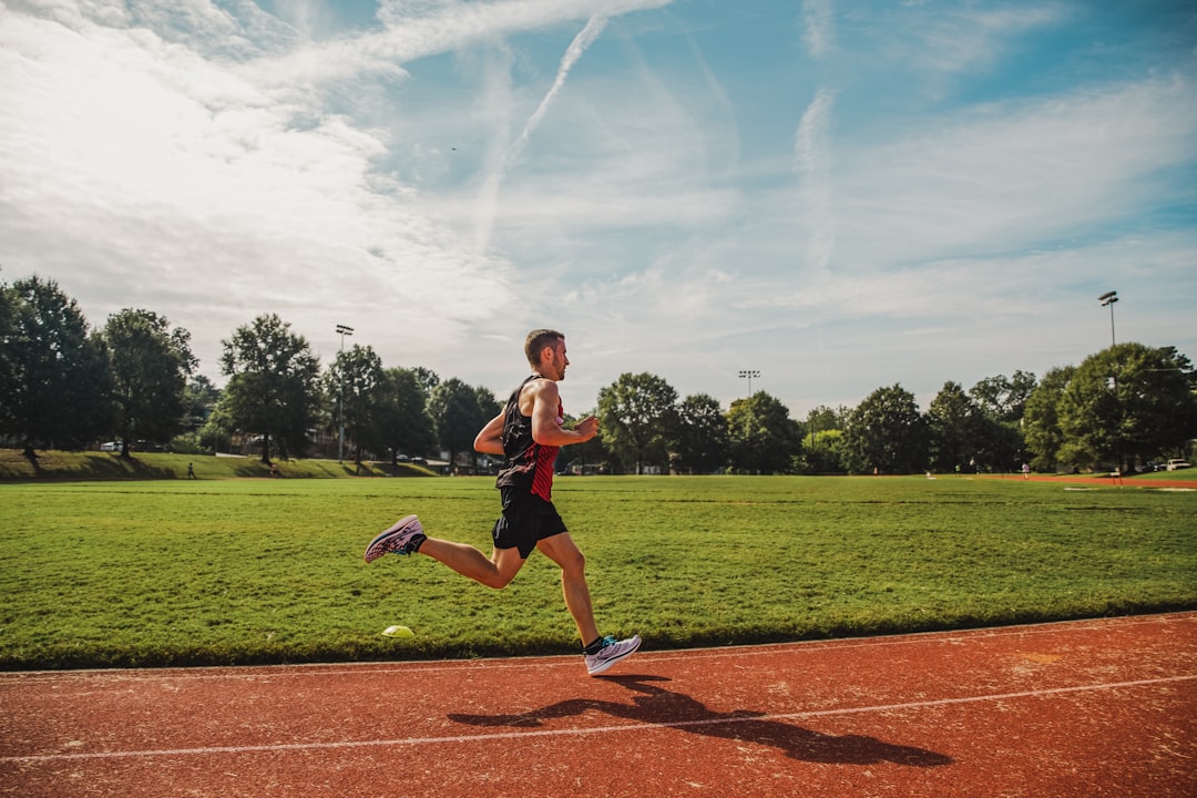 Runner on outdoor track during daytime training session showing steady effort