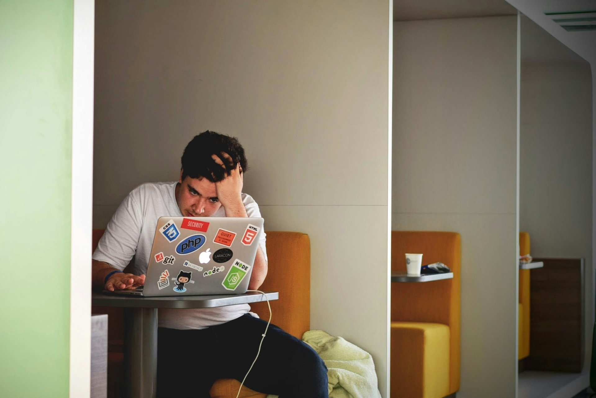 A person sitting with a laptop looking overwhelmed by data and notifications