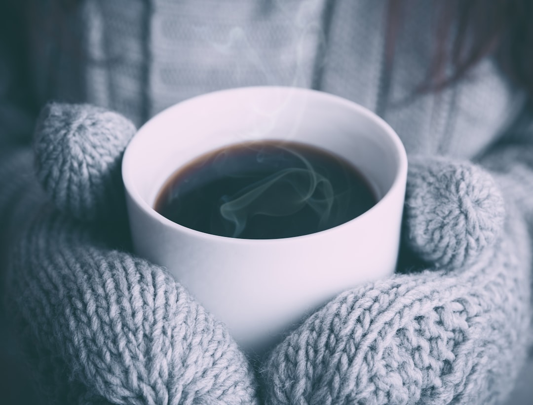 Person warming both hands around a white ceramic mug, a practical way to restore finger blood flow before a heart rate reading