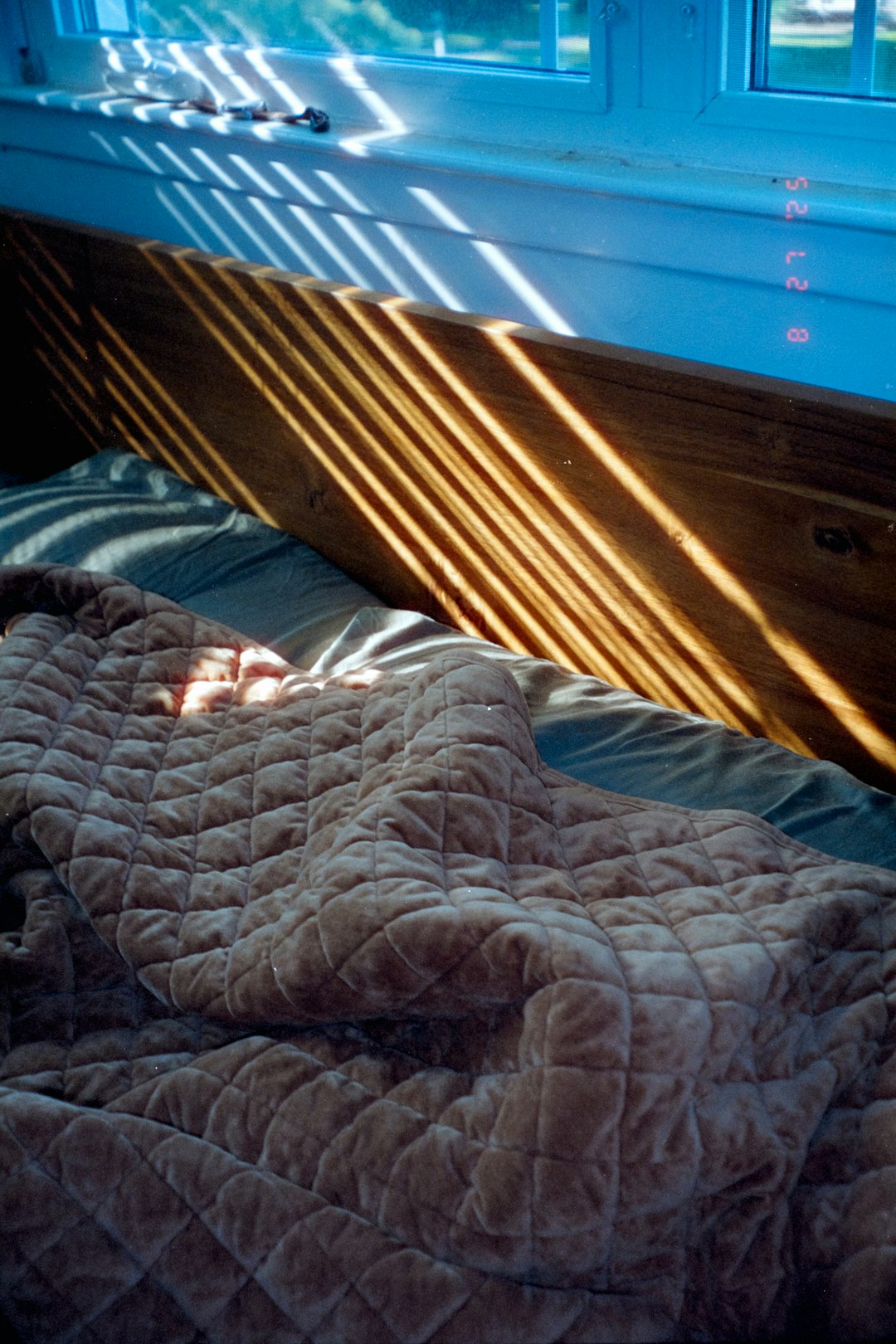 Morning sunlight through blinds falling across an unmade bed, showing the moment a low sleep score lands