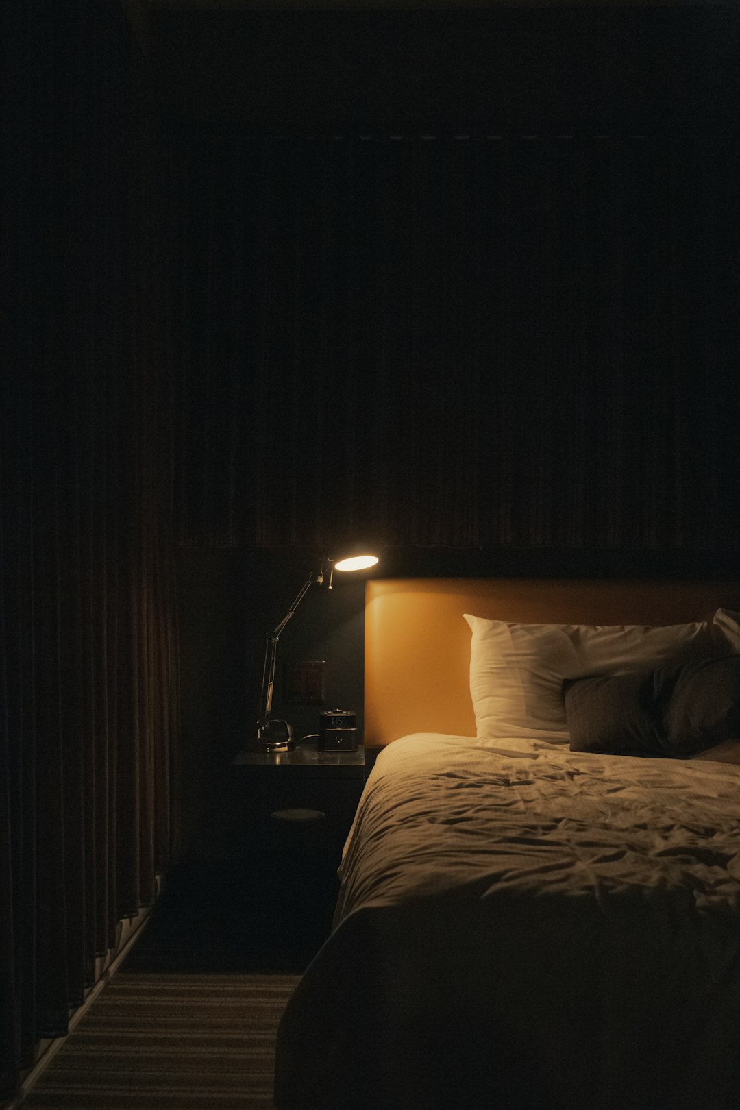 Bedside lamp glowing beside an unmade bed at night, showing the quiet bedroom context where alerts would interrupt sleep
