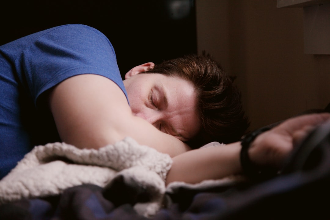 Man in blue shirt sleeping on side, illustrating fragmented sleep that can briefly raise nighttime heart rate