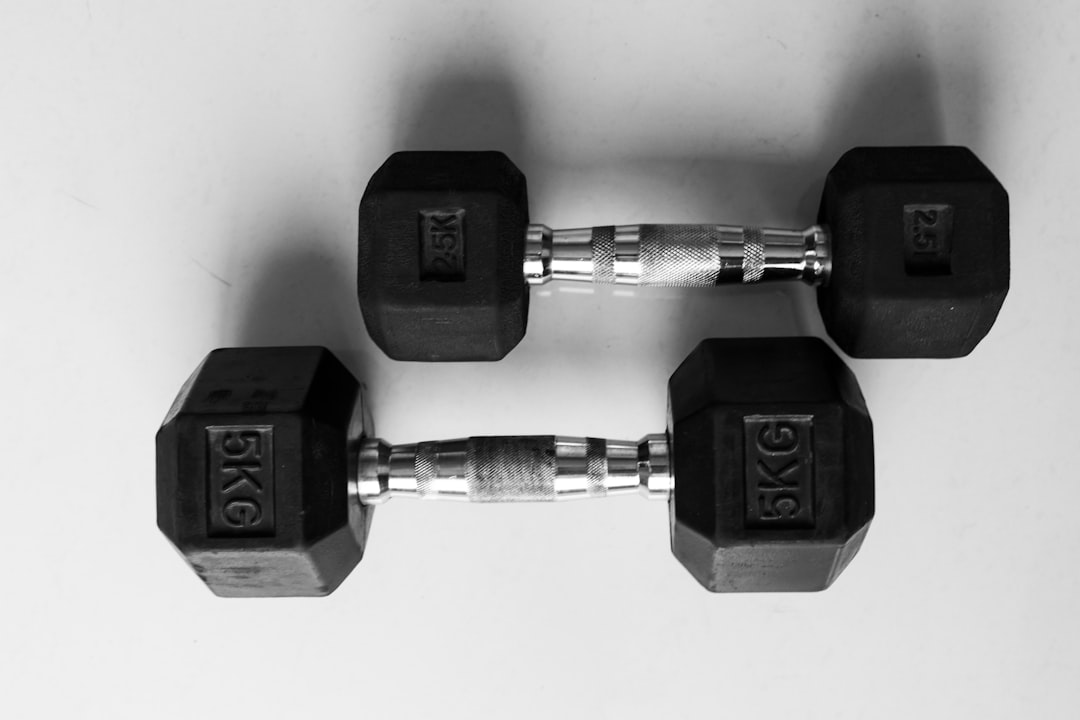 Close-up of black dumbbells stacked in a gym, representing the grip load that compresses finger tissue during weightlifting