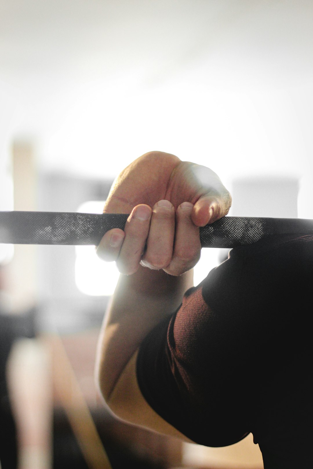 Hand wrapped around a gym bar with a smart ring visible, showing how grip pressure and bar contact shift the ring during a lift