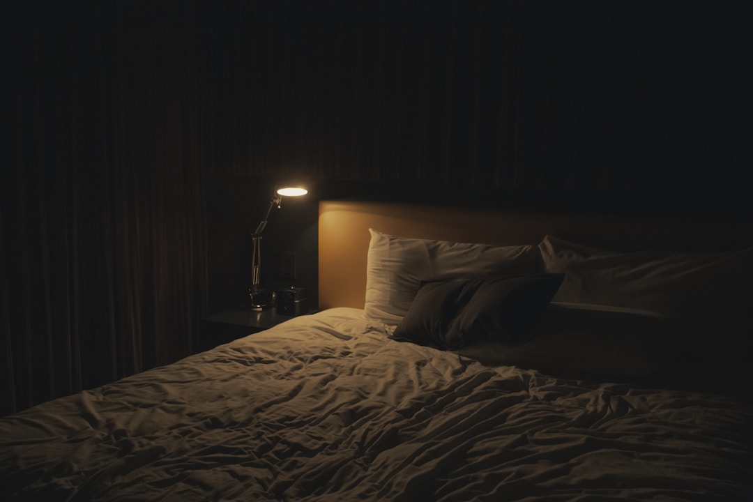 A bedside lamp glowing in a dark bedroom, representing the sleep onset delay and lighter sleep that caffeine causes at night