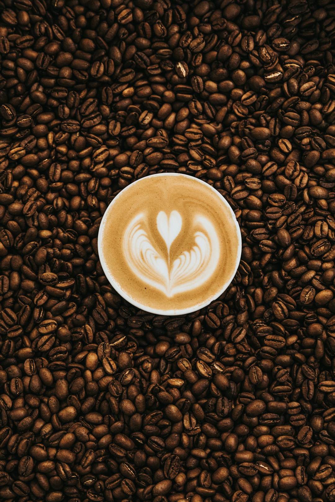 A latte with heart-shaped foam art, representing how caffeine creates a misleading recovery signal in heart rate variability readings