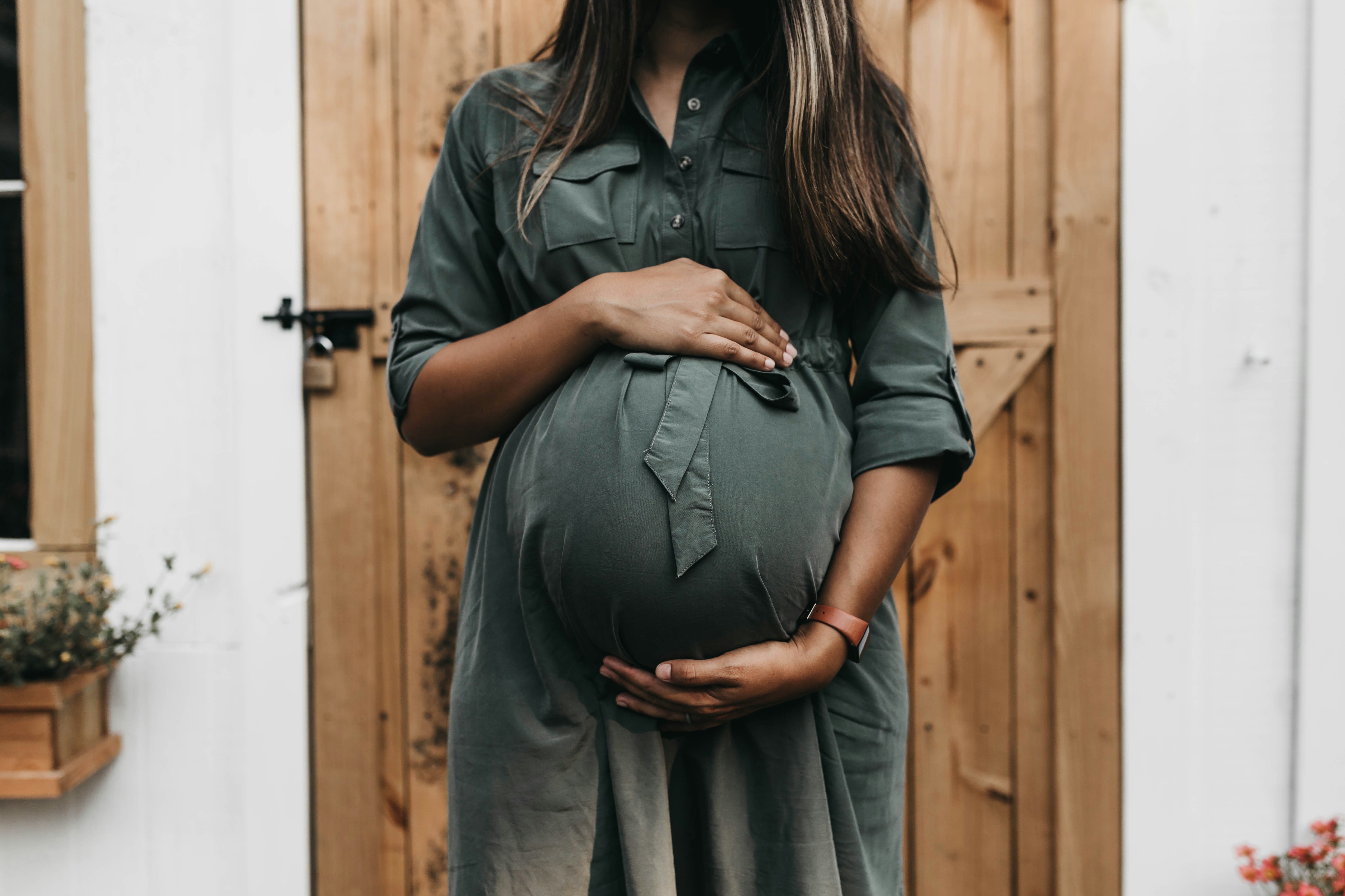 A pregnant woman wearing a smart ring, with abstract biometric data lines flowing around her finger