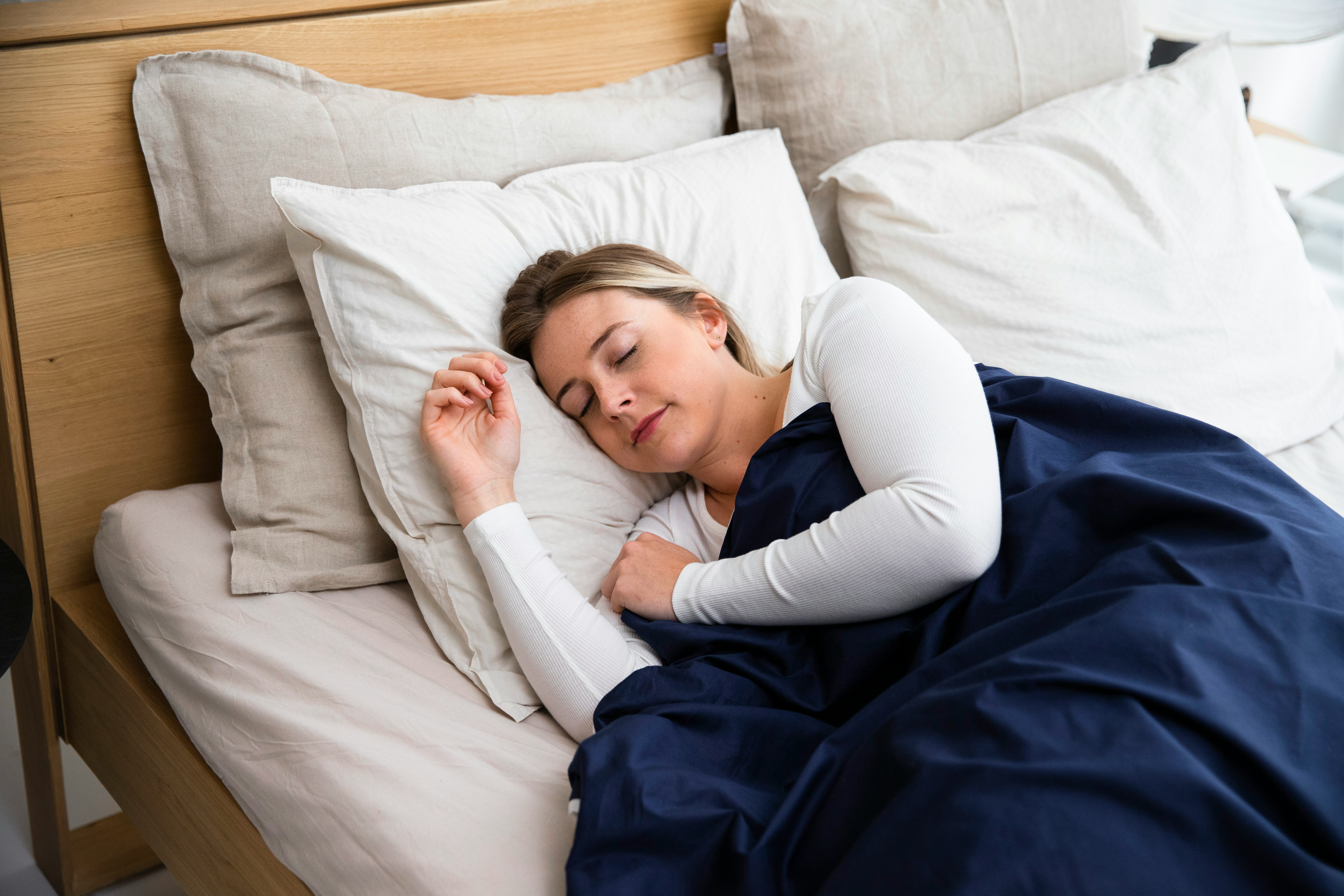 A pregnant woman sleeping, with a smart ring visible on her finger. Sleep tracking algorithms trained on non-pregnant populations misinterpret the fragmented sleep architecture of pregnancy as poor sleep quality rather than a normal physiological adaptation.