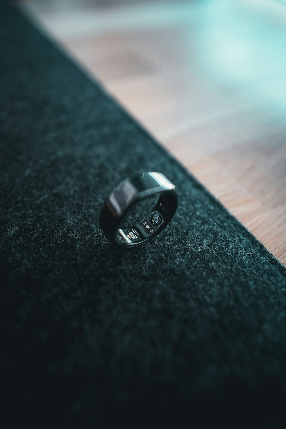 A smart ring worn on a finger with abstract health data visualizations around it, illustrating how wearable sensors track heart activity