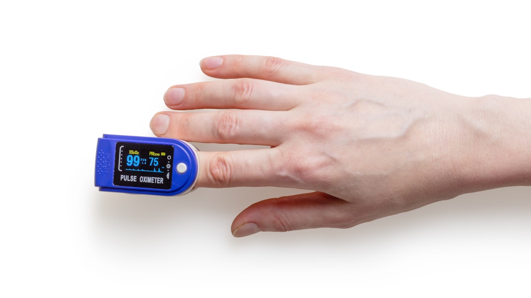 A pulse oximeter clipped on a finger showing how optical sensors measure blood flow through the skin, the same principle used in smart ring PPG sensors